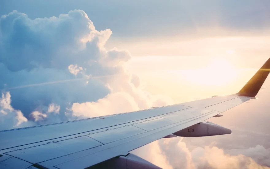 Airplane wing above clouds at sunset