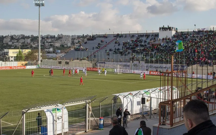 Football match at Dora Stadium with supporters in the stands
